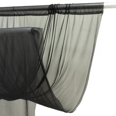Black sheer curtain hanging on rod with white backdrop
