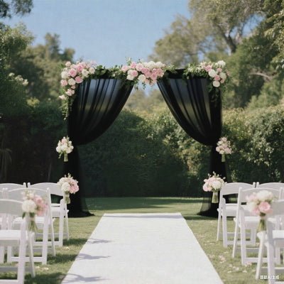 Elegant wedding arch with black drapes and floral arrangements in a garden setting.