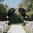 Elegant wedding arch with black drapes and floral arrangements in a garden setting.