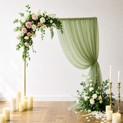 Elegant wedding floral arch with sage green drapery and candles