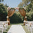 Elegant wedding arch draped in fabric, adorned with flowers, set in a lush garden.