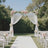 Wedding arch adorned with flowers and white drapes in a garden setting.