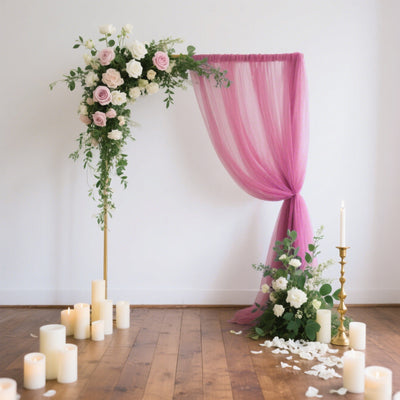 Wedding ceremony backdrop with pink drapery and floral arrangements.