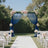 Wedding arch with blue drapes and floral arrangements in a garden setting.