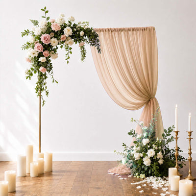Floral wedding arch with blush drapery, roses, candles, and greenery decor