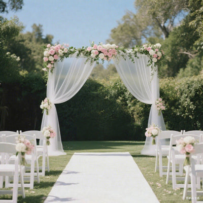 Wedding arch decorated with pink flowers and drapes in a garden setting.
