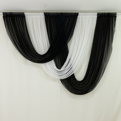 Black and white draped sheer curtains on a plain backdrop 