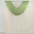 Green and ivory sheer curtains draped over a window rod