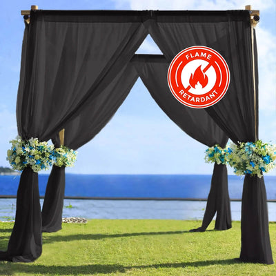 Black outdoor wedding arch draped in flowers with a flame retardant label.