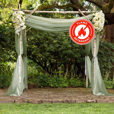 Flame retardant wedding arch with greenery and floral accents in an outdoor setting.