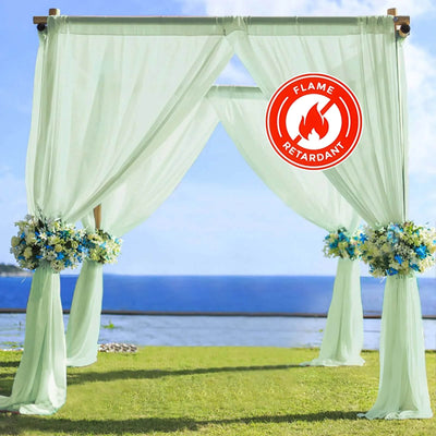 Flame-retardant wedding arch draped with sheer fabric and floral arrangements.