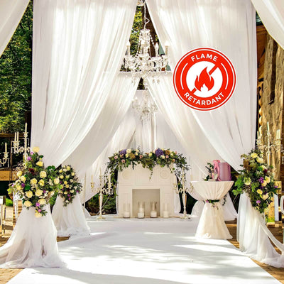 Elegant outdoor wedding decor with floral arrangements and draped fabric.
