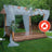 Flame retardant outdoor gazebo with draped fabric and greenery in a garden setting.