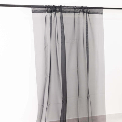 Sheer black curtain draped on a rod against a white background.