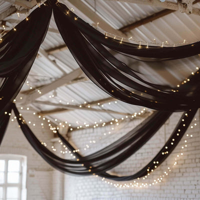 Decorative black drapery with fairy lights in a spacious venue setting.
