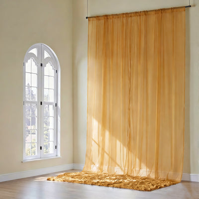 Sheer golden curtains elegantly draping from a window in a bright room.