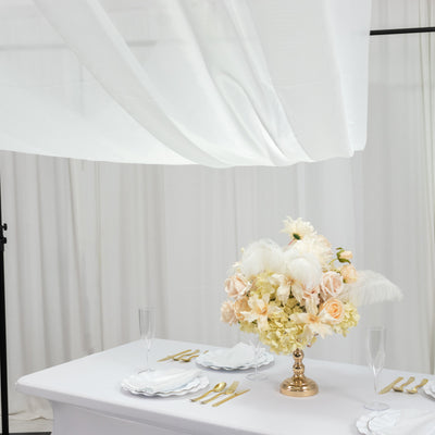 Elegant floral centerpiece on a table with gold accents and white drapery.