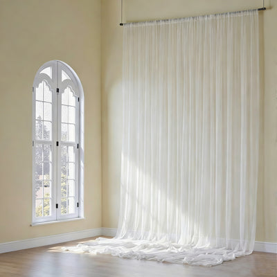 Sheer white curtain draping elegantly by a sunlit window.
