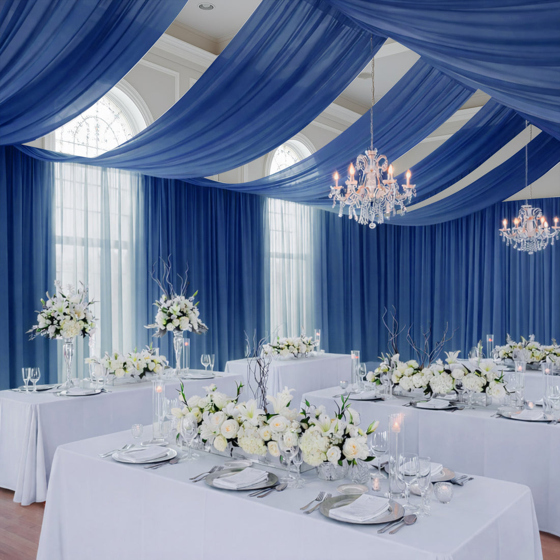 Elegant wedding reception setup with blue drapes and floral centerpieces.