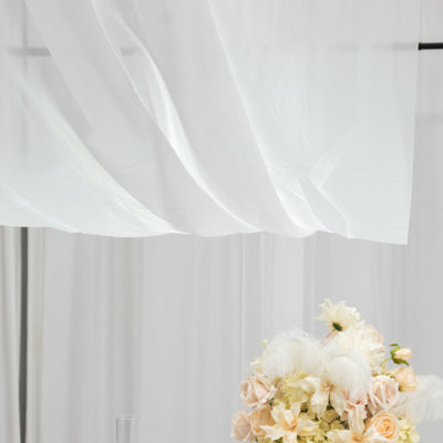 Delicate sheer fabric draping over a floral arrangement in soft pastel colors.