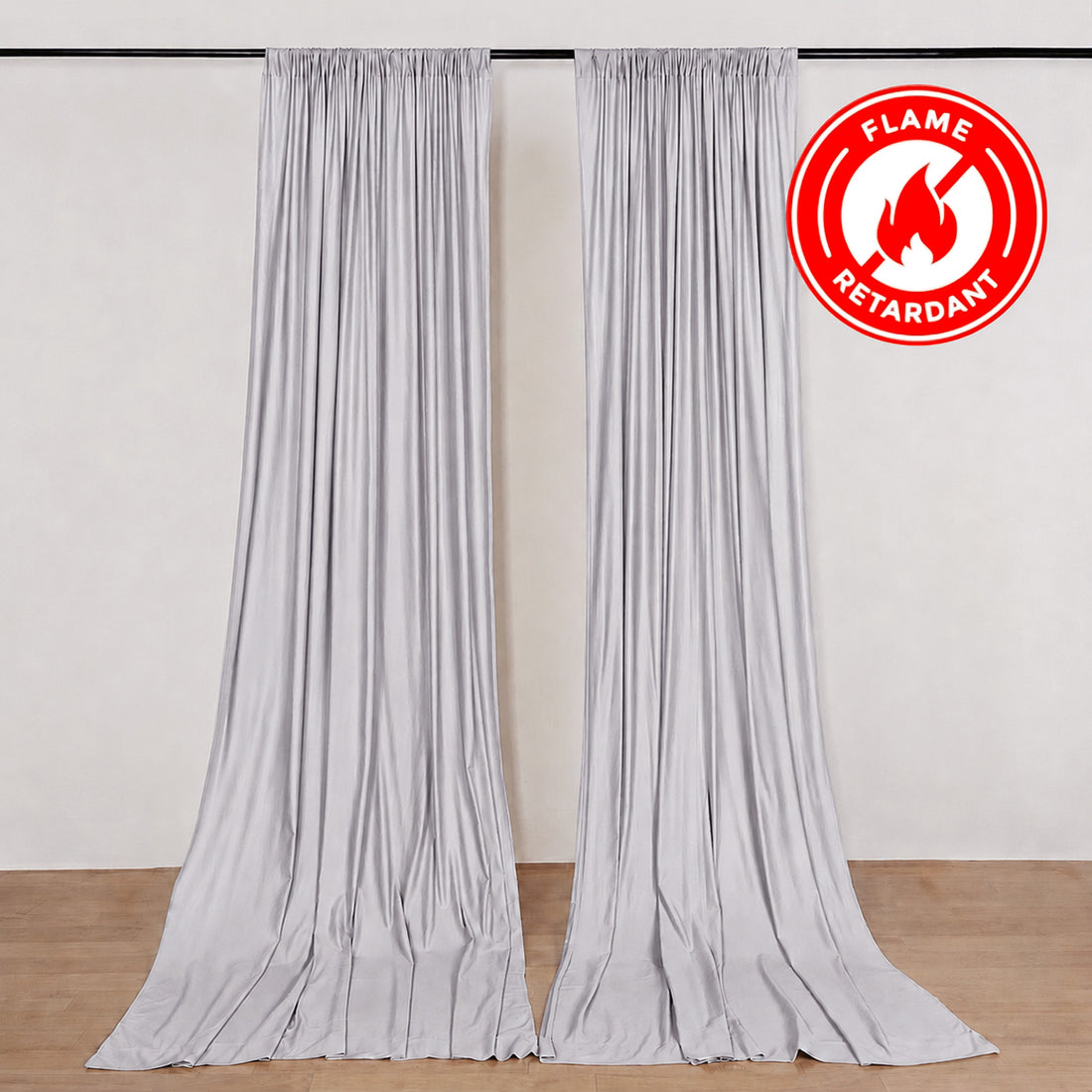Flame retardant silver curtains hanging on a wall with floor-length drape