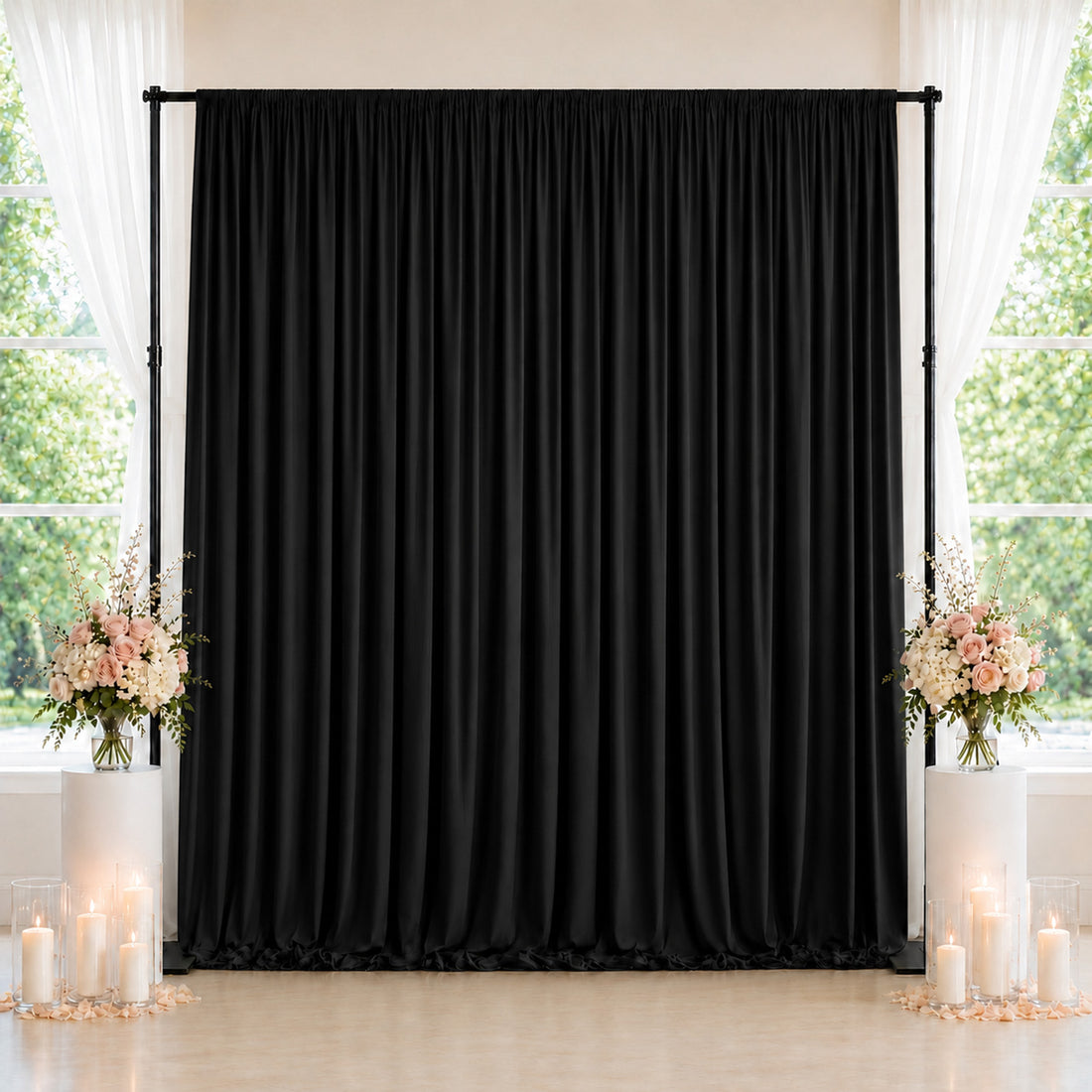 Black wedding backdrop with floral arrangements and candles by window
