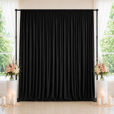 Black wedding backdrop with floral arrangements and candles by window
