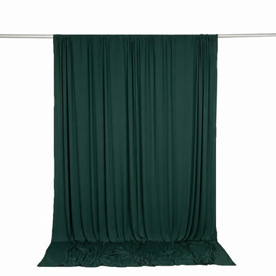 Dark green draped curtain on a rod against a white background