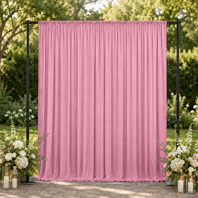 Pink draped wedding backdrop with floral arrangements in an outdoor garden setting