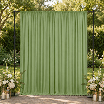 Green outdoor event curtain backdrop with floral arrangements and lanterns