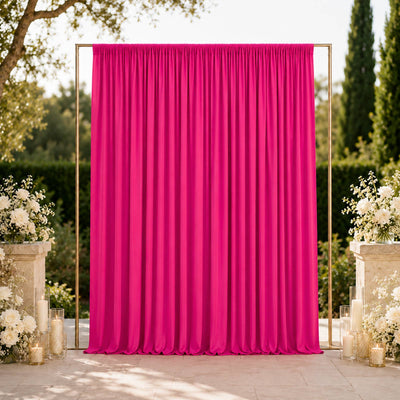 Pink wedding backdrop curtain with floral arrangements and candles outdoors