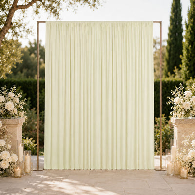 Elegant outdoor wedding backdrop with ivory drape, floral arrangements, and candles