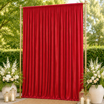 Red velvet backdrop with gold stand, floral arrangements, and lanterns outdoors