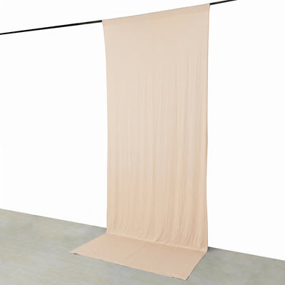 Beige backdrop curtain hanging from a black rod in a minimalist studio setting