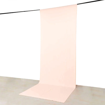 Minimal blush pink fabric backdrop hanging from a black crossbar on white studio wall