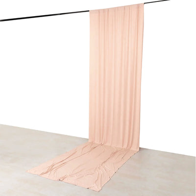Blush pink sheer draped curtain hanging from ceiling rod with pooled fabric on floor