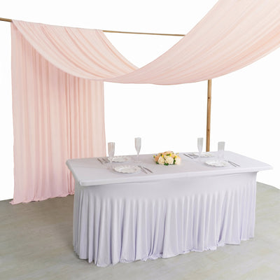 Pastel pink wedding table draped with sheer canopy and floral centerpiece