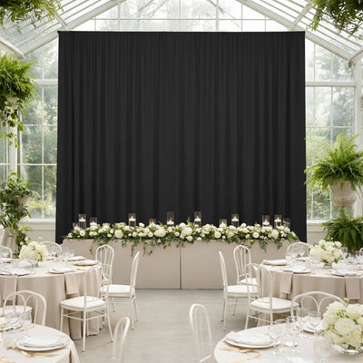 Elegant black curtain backdrop for a wedding reception with floral decor.