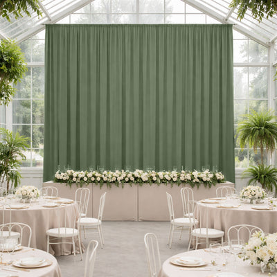 Elegant green backdrop in a decorated event space with floral arrangements.