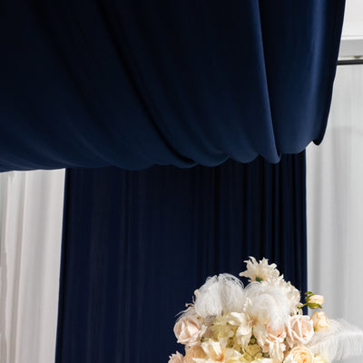 Elegant floral arrangement under navy drapery backdrop.
