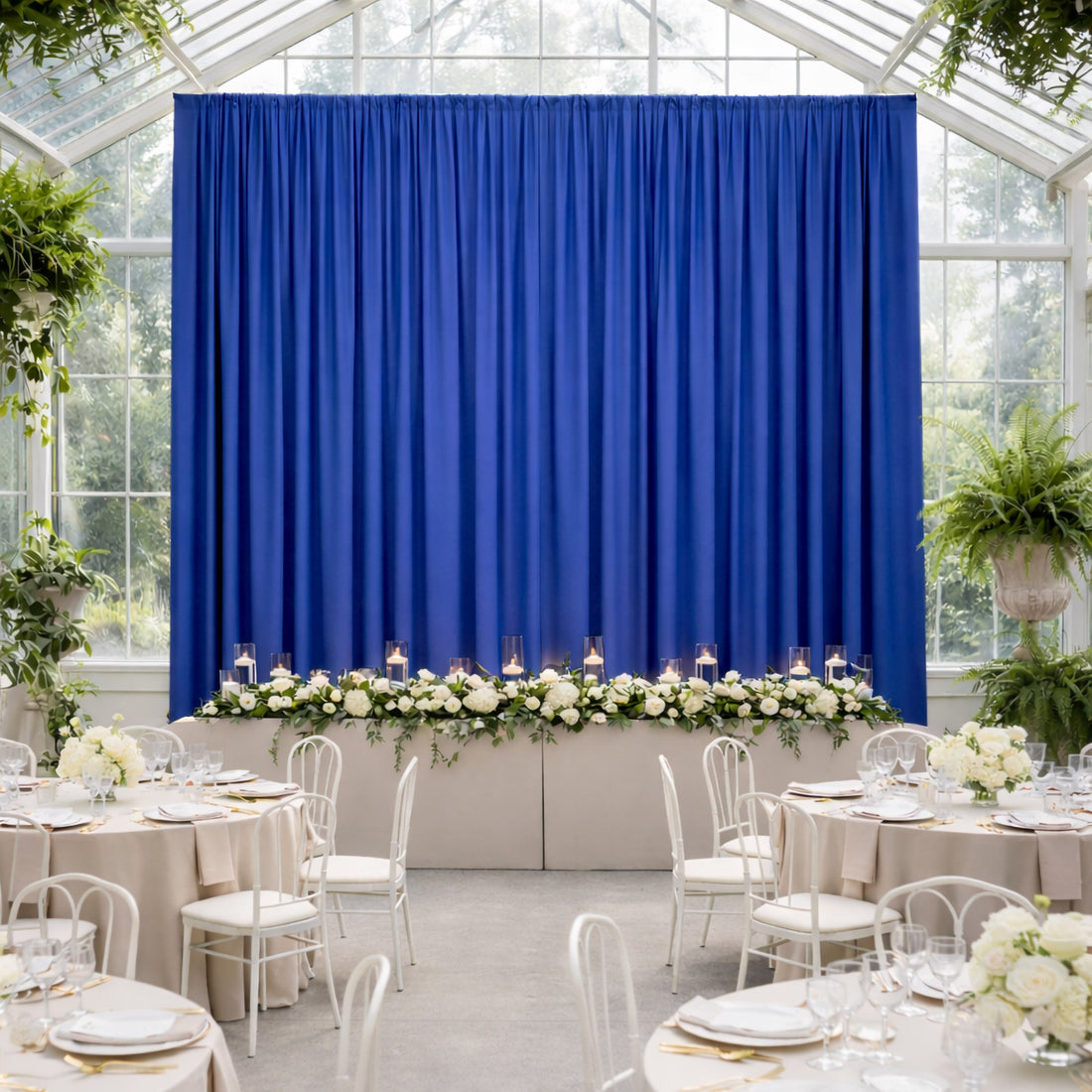 Elegant wedding reception setup with blue curtains and floral table decoration.