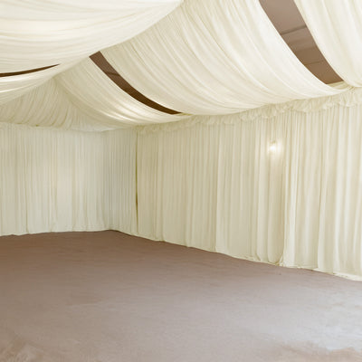 Elegant cream drapery and soft lighting in a spacious interior setting.