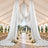 Elegant outdoor wedding ceremony tent with white drapery and floral aisle