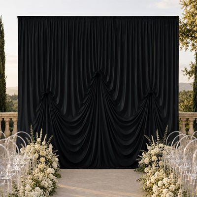 Elegant outdoor wedding backdrop with black drapery and white floral arrangements