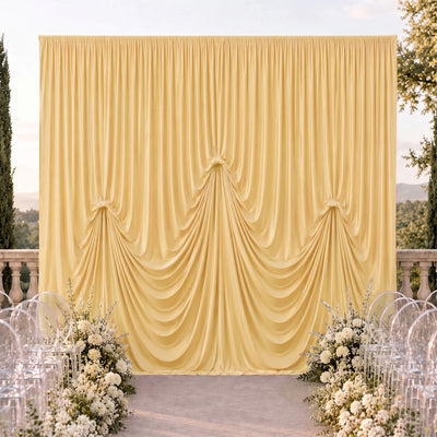Elegant outdoor wedding backdrop with draped gold curtain and white floral arrangements