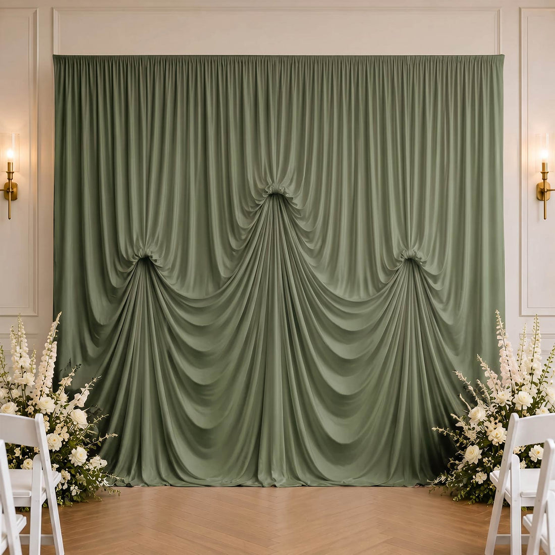 Elegant sage green draped wedding backdrop with white floral arrangements