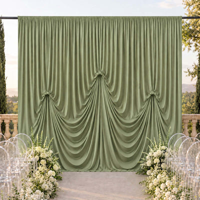 Elegant sage green draped wedding backdrop with floral aisle decor outdoors