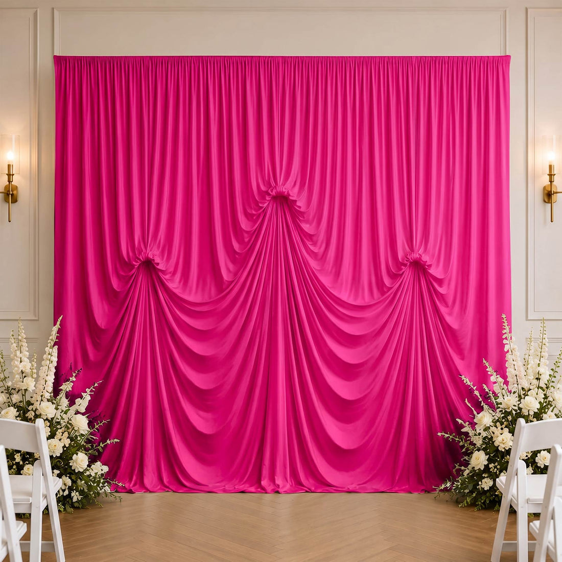 Bright pink wedding backdrop with draped satin curtains and white floral arrangements