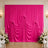 Bright pink wedding backdrop with draped satin curtains and white floral arrangements