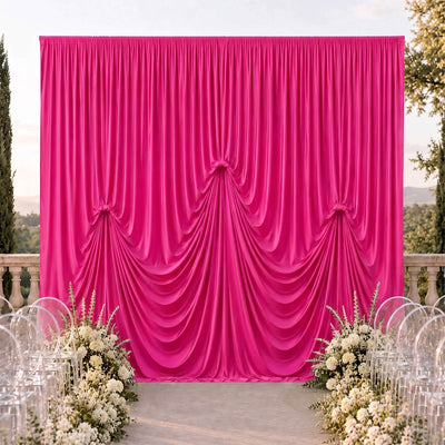 Pink draped wedding backdrop with floral aisle and clear chairs outdoors